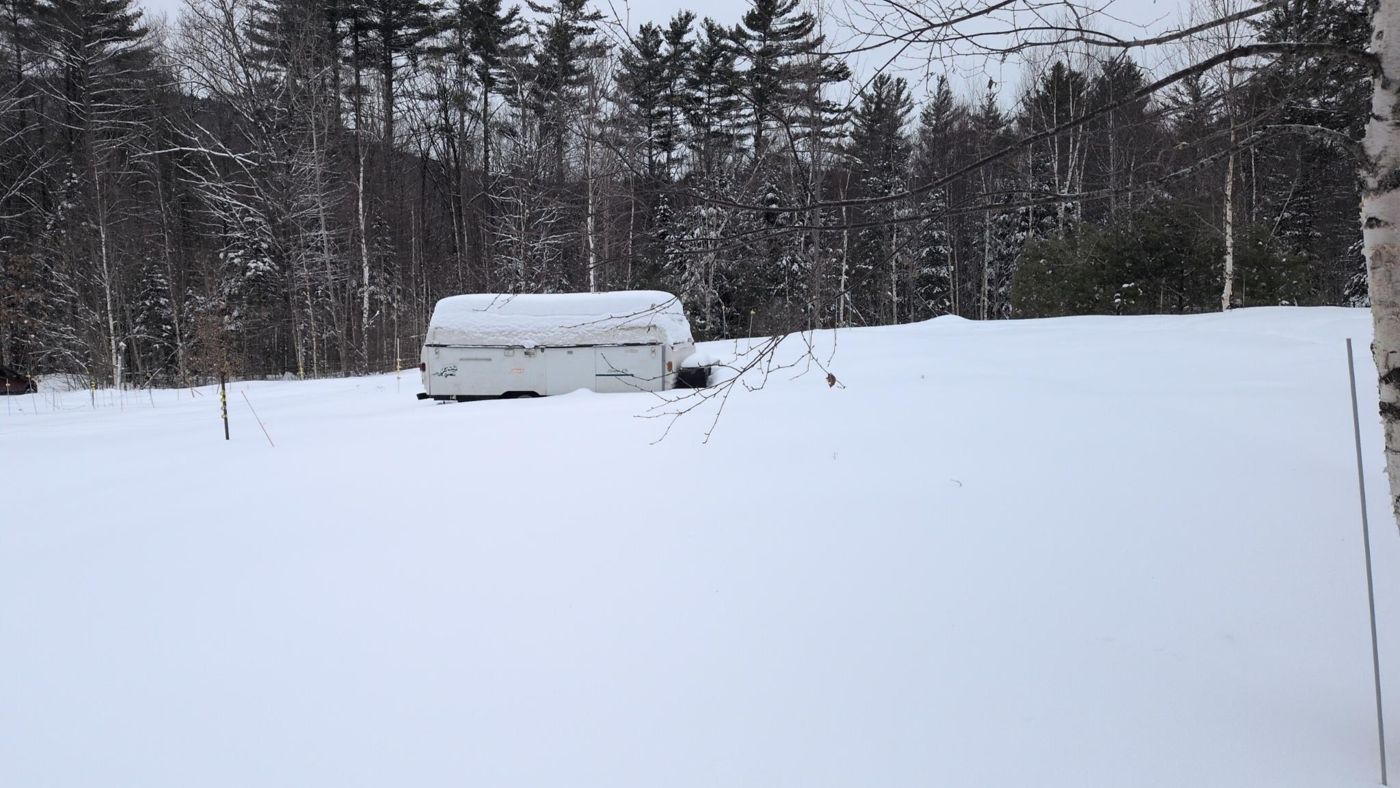 snowy clearing with buried picnic table at Bartertowne, Canaan New Hampshire